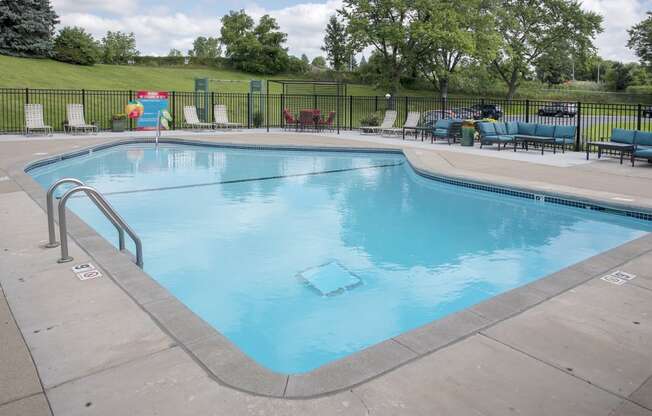 a swimming pool with chaise lounge chairs and trees in the background