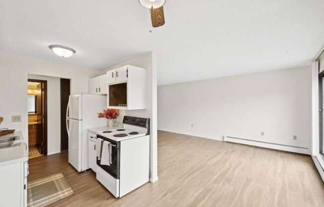 an empty living room with a kitchen with a stove and refrigerator