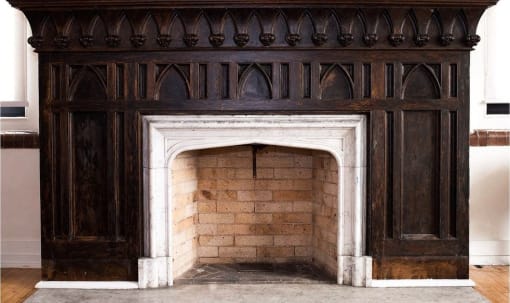 an old fireplace with a wooden mantel and a brick wall