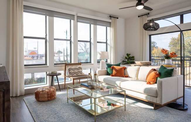 A living room with a white couch, a glass coffee table, and a ceiling fan.