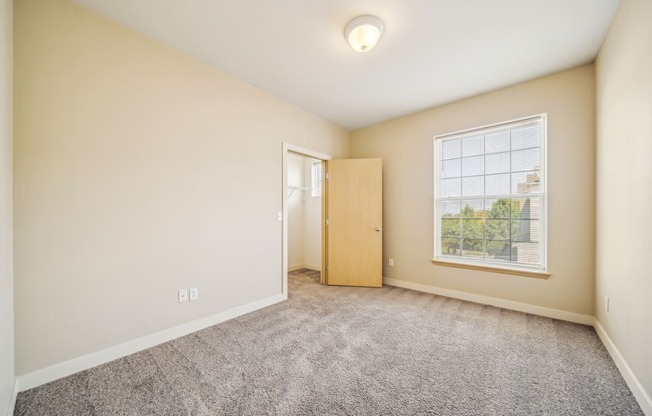 a spacious living room with carpet and a door to a bedroom