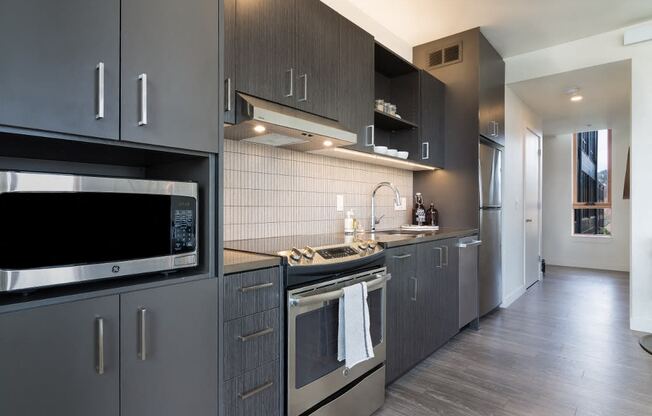 Portland, OR Apartments for Rent - Muse Apartments Kitchen With Stainless Steel Appliances, Sleek Wood Cabinetry, Hardwood Floors and Modern Finishes