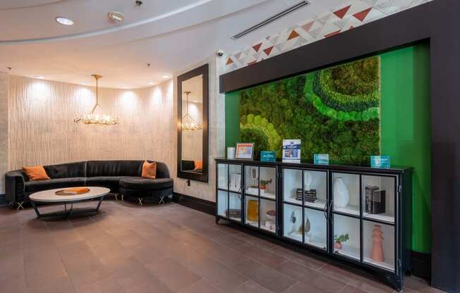 the lobby of a building with couches and a display case with a green wall
