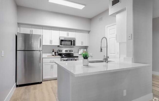 A modern kitchen with a stainless steel refrigerator and a white island.