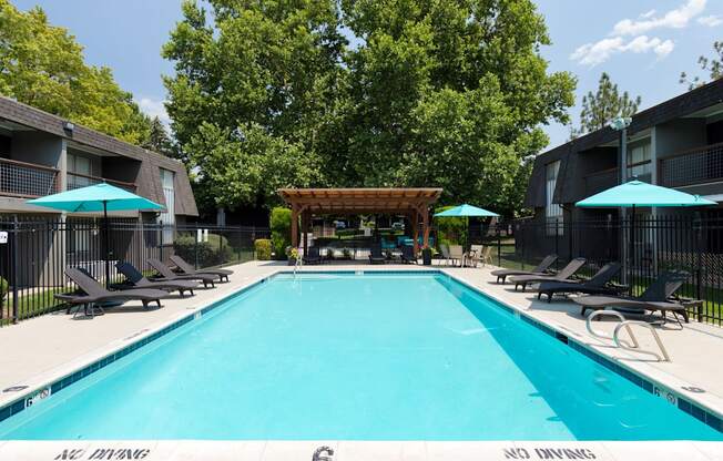 A large swimming pool surrounded by lounge chairs and umbrellas.