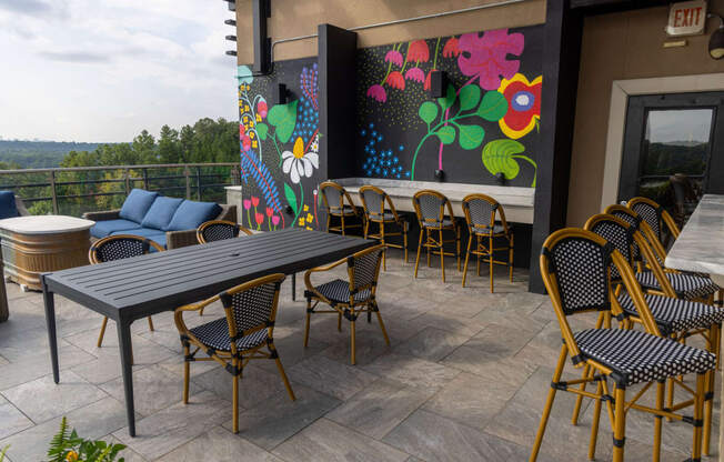 a patio with tables and chairs and a mural on the wall