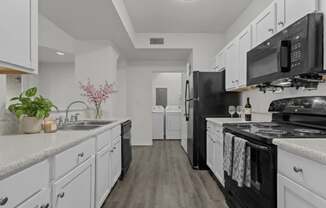 A kitchen with black appliances and white cabinets.