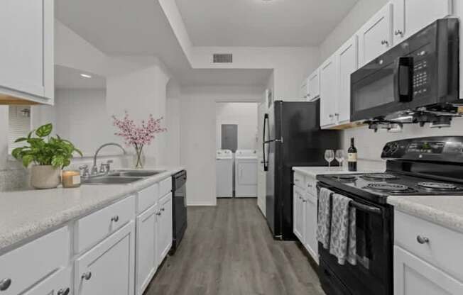 A kitchen with black appliances and white cabinets.