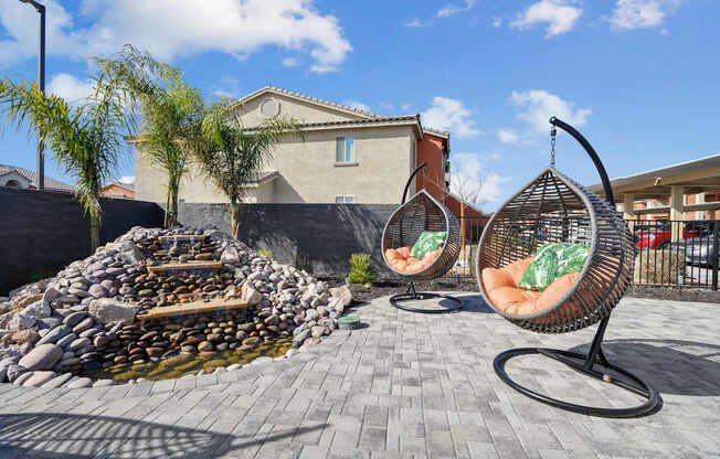 A patio with two hanging chairs and a fire pit.
