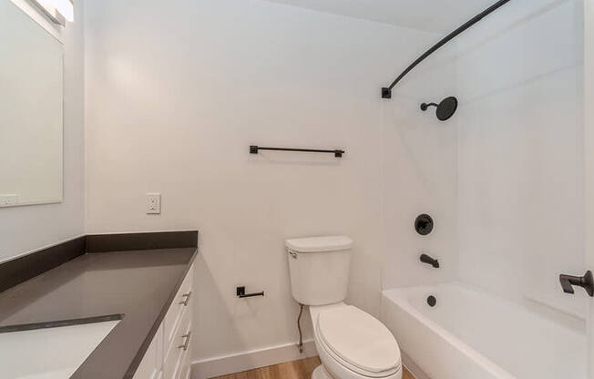 Model Bathroom with White Cabinets and Wood-Style Flooring at Palmilla Apartments located in San Diego, CA.