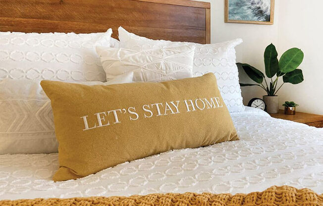 lets stay home pillow on a bed