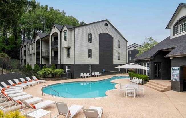 a swimming pool with chairs around it in front of a building