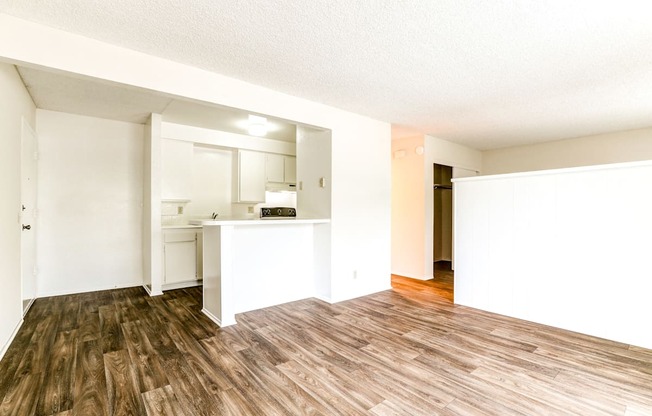 an empty living room and kitchen with a hard wood floor