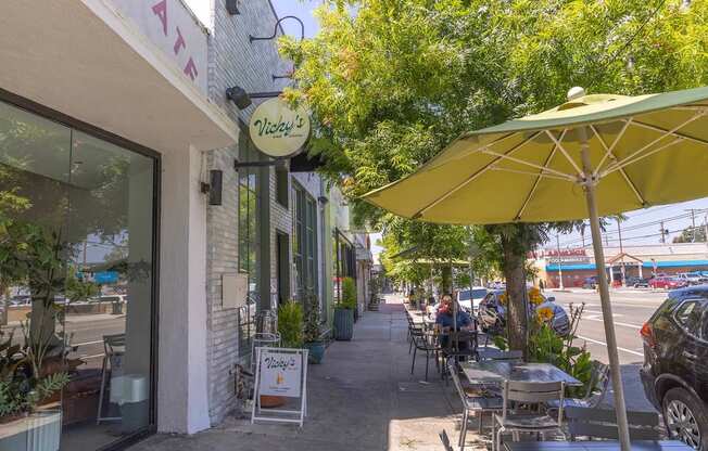 A yellow umbrella is on a table outside of a restaurant.