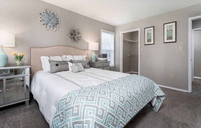 a bedroom with grey walls and a large bed with a blue and white comforter
