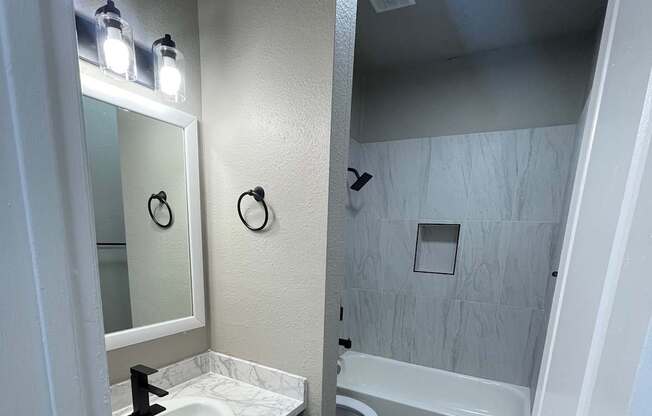 A bathroom with a toilet, sink, and mirror.