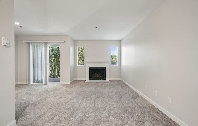 A spacious living room with a fireplace and a carpeted floor.