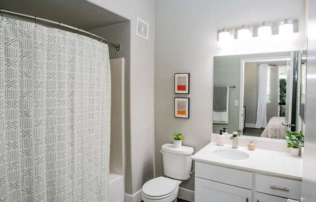 A white bathroom with a toilet, sink, and shower curtain. at Octave Apartments, Nevada