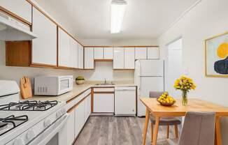 A kitchen with a white gas stove and a white refrigerator.