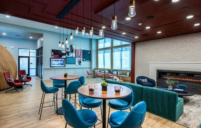 a lounge area with blue chairs and tables and a fireplace