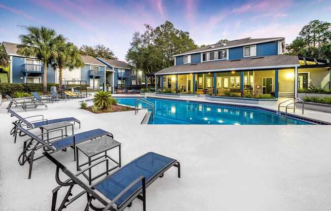 A pool with sun loungers and a building in the background.