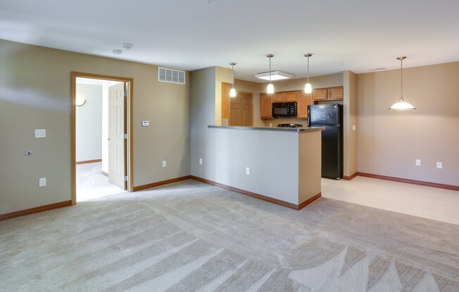 the living room and kitchen of an empty house with the door open