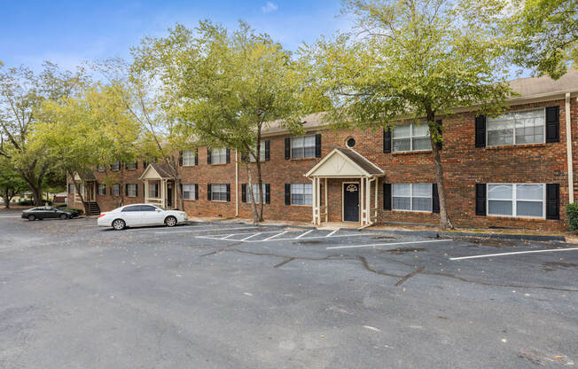 an empty parking lot in front of a brick apartment building