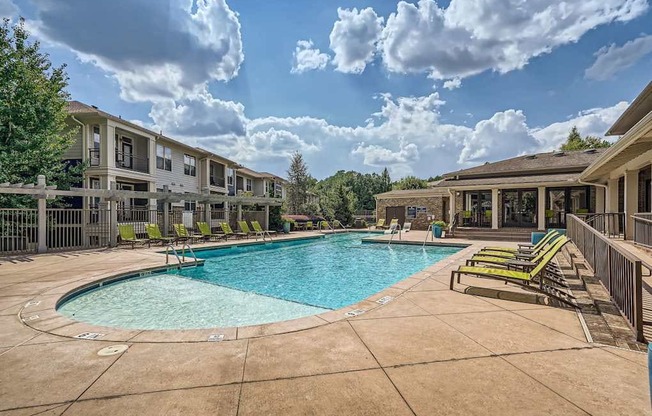 A swimming pool surrounded by lounge chairs and apartment buildings.