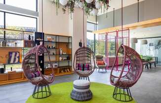 a lobby with two rattan chairs and a green rug