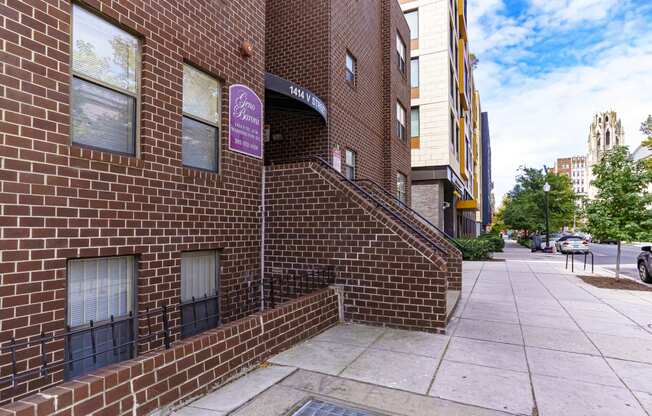 the side of a brick building with a staircase and a sidewalk