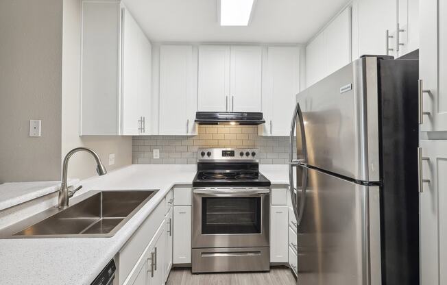 a kitchen with white cabinets and stainless steel appliances