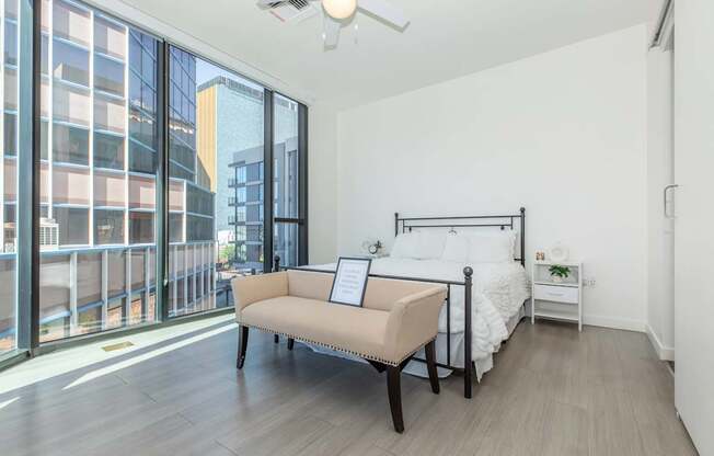 A bedroom with a large bed and a balcony overlooking a city.
