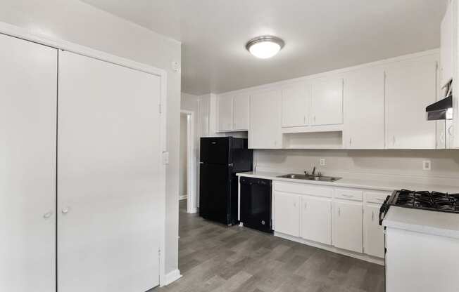 a kitchen with white cabinets and a black refrigerator