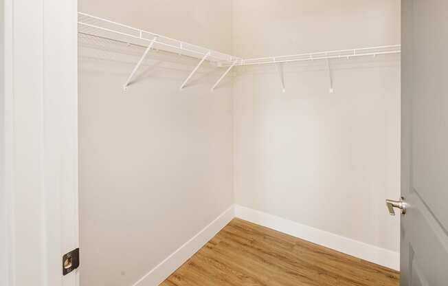 a bedroom with white walls and a wood floor and a closet with white hangers at 44 West Luxury Living, Valley Park, MO, 63088