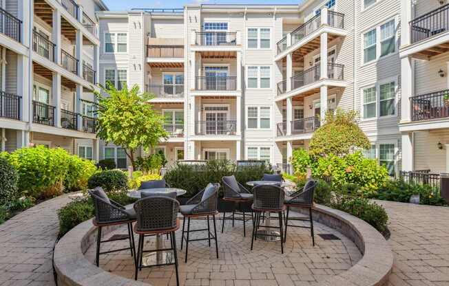 A patio with chairs and a table is in front of a building.