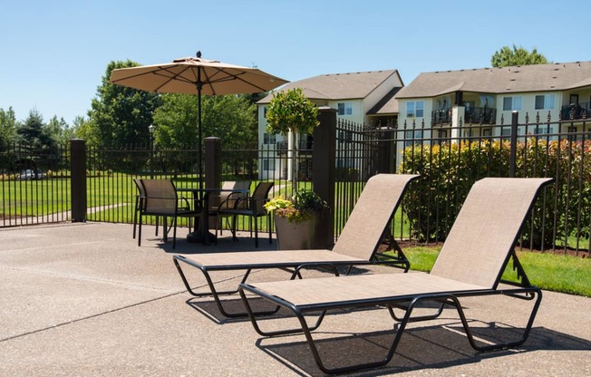 a patio with two lounge chairs and an umbrella