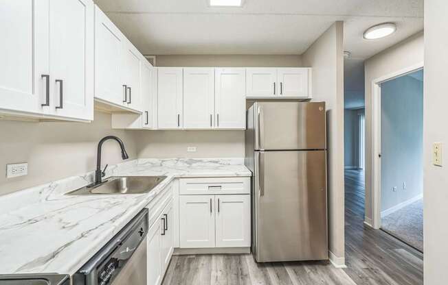 A kitchen with white cabinets and a stainless steel refrigerator.