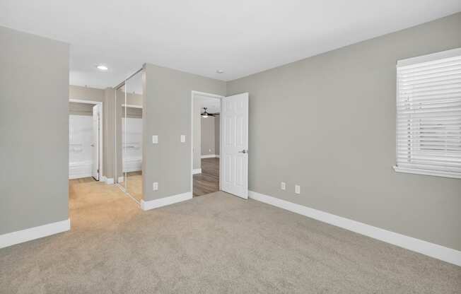 a spacious living room with carpet and a door to a bedroom