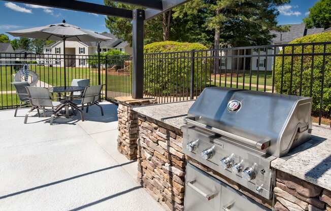 a patio with a grill and a table with chairs