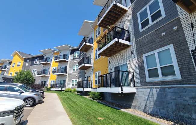 a row of apartments with balconies and cars parked in front