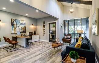 A modern living room with a black couch and a desk with a laptop.