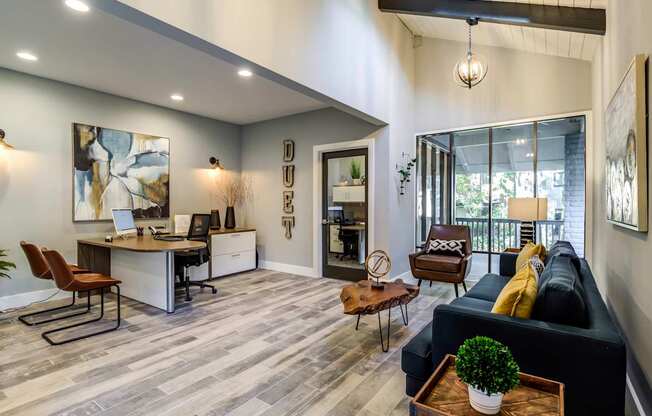 A modern living room with a black couch and a desk with a laptop.