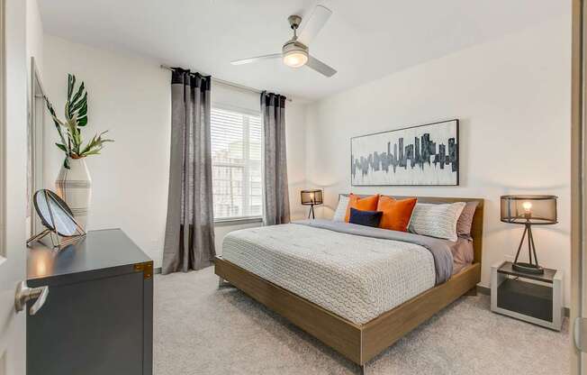 A bedroom with a bed, nightstand, and a painting on the wall.