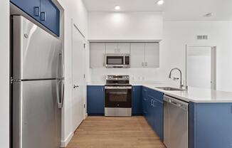 a kitchen with blue and white cabinets and stainless steel appliances