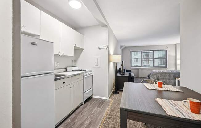 a kitchen and living room with white appliances and a wooden table