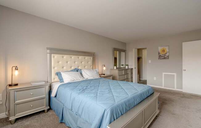 A bedroom with a blue bedspread and a white headboard.
