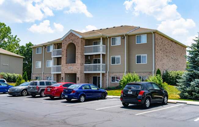 an apartment building with cars parked in a parking lot