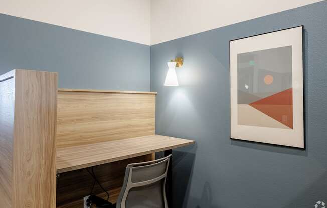 A desk with a chair and a picture on the wall.