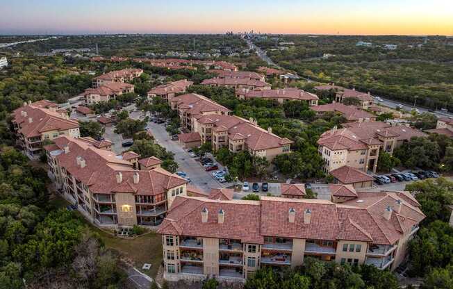 A sunset view of a large residential complex with multiple buildings and parking lots. at Bridge at Heritage Woods, Austin, Texas