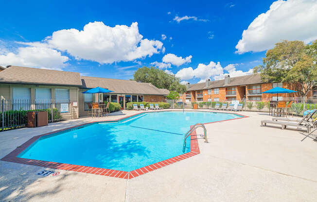 A large swimming pool surrounded by a fence and a building in the background.